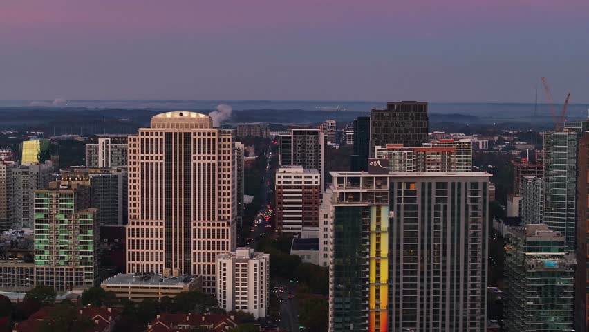 Aerial view of high-rise buildings and a red crane contrasting against the twilight sky and city lights, Atlanta, Georgia, United States.
