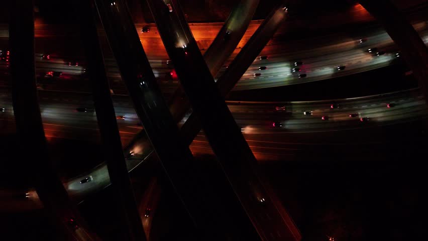 Aerial view of bright car lights streaking across the dark highway interchange, creating a stunning contrast of light and shadow, Atlanta, Georgia, United States.
