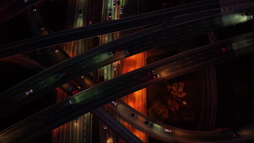 Aerial view of a complex highway interchange illuminated at night with streaks of headlights and taillights weaving through the dark, Atlanta, Georgia, United States.