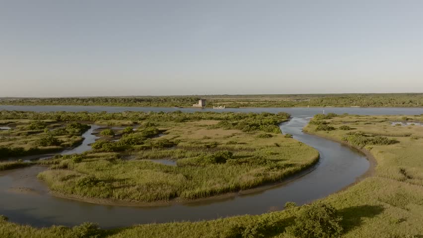 Aerial view of winding waterways cutting through marshlands, creating a serene landscape with a fort in the background, St. Augustine, Florida, United States.