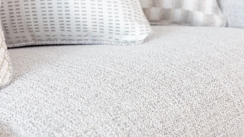 Camera sweeps along spotless upholstery, highlighting soft pillows and clean lines