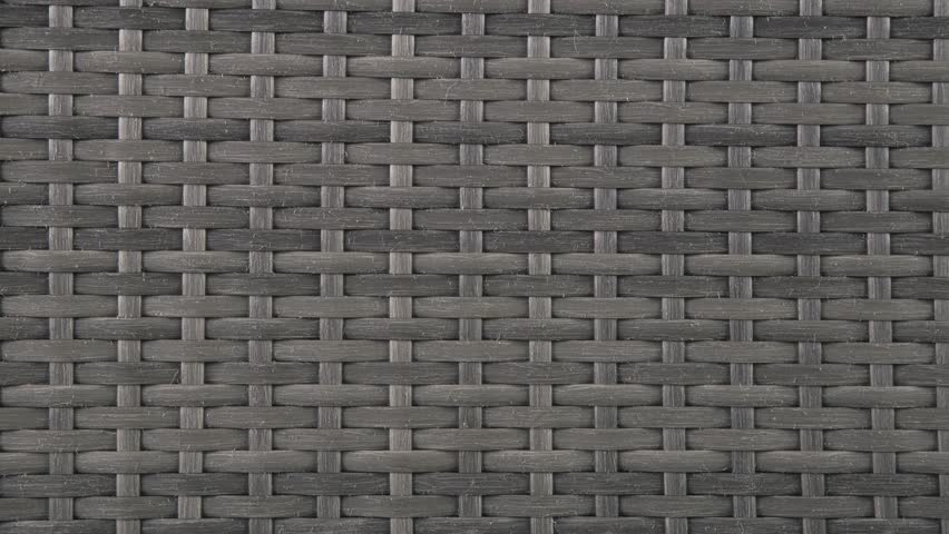 Camera closes in on rich wicker weave of patio chair under daylight