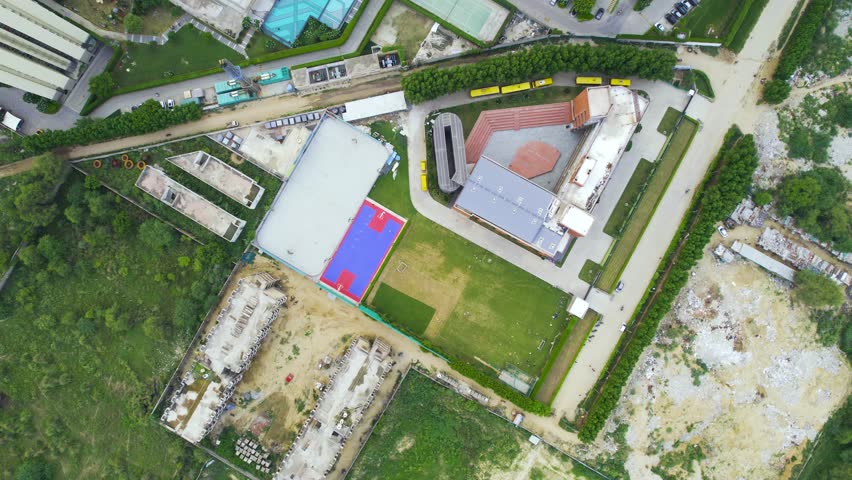 Aerial drone shot straight down into sports complex with basketball, swimming, tennis belonging to elegant housing complex with gardens and tall towers