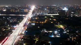 Aerial drone hyperlapse shot of Mumbai Delhi expressway showing fast moving cars in the middle of cityscape at night with skyscrapers in distance - Powered by Shutterstock - Get 15% off with code: PIKWIZARD15