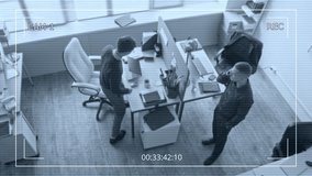 Security camera footage of male manager walking around office room equipped with partitioned desk talking on smartphone then passing phone to colleague during business planning conversation - Powered by Shutterstock - Get 15% off with code: PIKWIZARD15