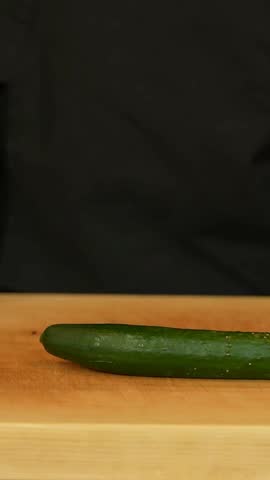 Close-Up of Sushi Chef Cleaning Sharp Knife Over Fresh Cucumber on Wooden Cutting Board Before Food Preparation – 4K Ultra HD Culinary Footage