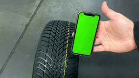 Mechanic driver hand inspecting wheel tire with mobile smartphone green screen.Tread tyre wear indicator check test at car service center. protector control during maintenance - Powered by Shutterstock - Get 15% off with code: PIKWIZARD15