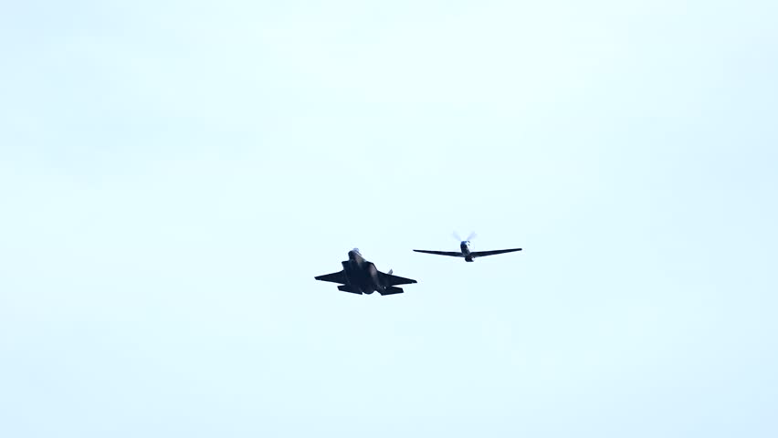 The F-35 fighter jet flies at a close distance to the P-51 Mustang aircraft.