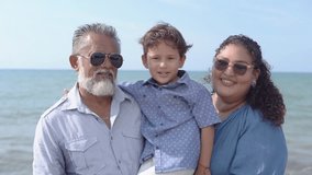 Multigenerational hispanic family sharing joyful moments during beach vacation, capturing loving connection between grandfather, mother, and grandson against sunny oceanfront backdrop - Powered by Shutterstock - Get 15% off with code: PIKWIZARD15