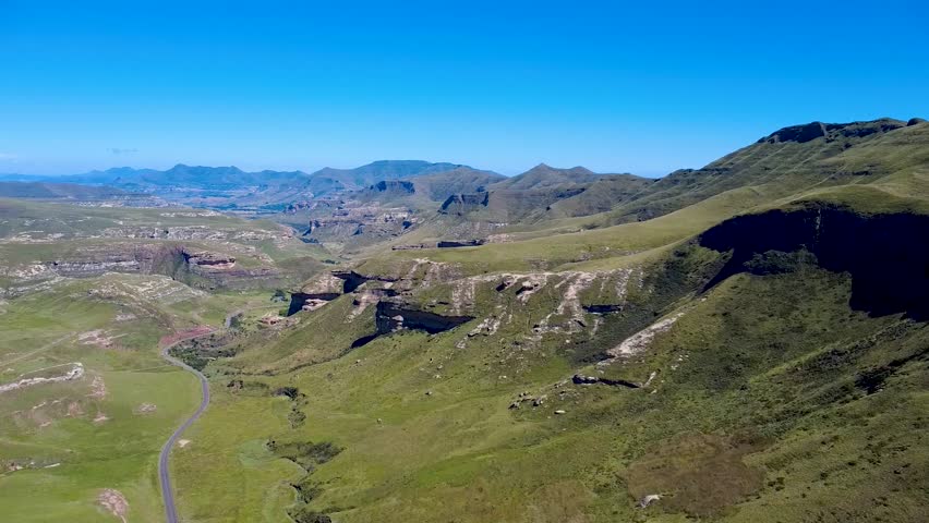 Sideways aerial view of a vast national park featuring a single winding road. Perfect for nature, travel, and adventure projects.