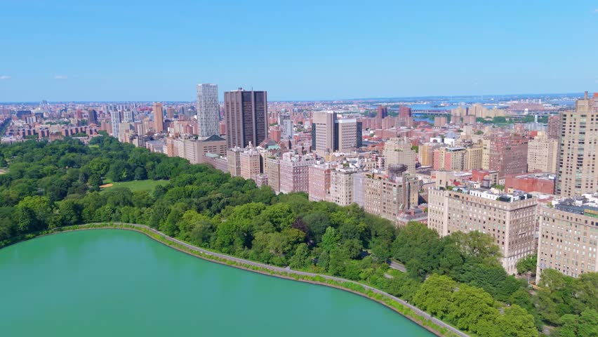 Green Park and lake in central park and high-rise residential apartments in New York City. Aerial approaching wide shot. Sunny day in summer season.