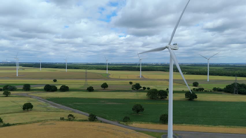 Renewable energy wind turbine spinning in green fields England drone view