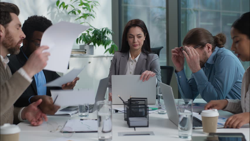 Stressed unhealthy Caucasian team leader businesswoman holding head ache headache pain suffering medicine multiethnic colleagues diversity business people arguing conflict shouting yelling in office