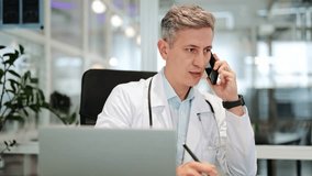 Handsome professional male doctor in a white lab coat and stethoscope, appearing focused, is actively engaging in a mobile phone call at an office desk, with a laptop open. - Powered by Shutterstock - Get 15% off with code: PIKWIZARD15
