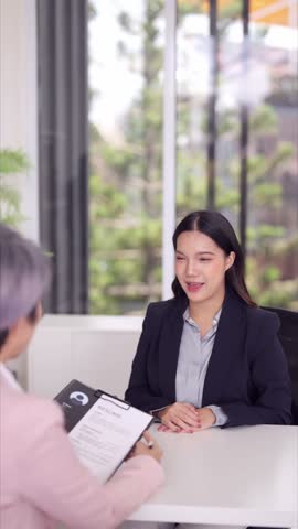 Young adult Asian woman attends professional job interview discussing career advancement in a bright corporate office setting
