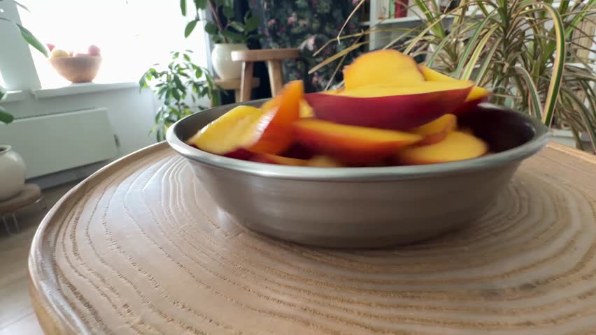 A bowl of fresh, vibrant sliced peaches (or nectarines) on a wooden surface. Perfect for healthy eating, summer fruit concepts, and natural food backgrounds.