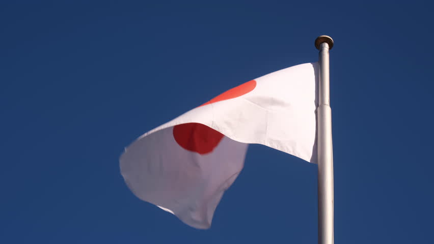 The flag of Japan waving in the wind with cloud and sky background.