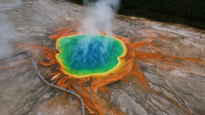 Aerial view of the vibrant Grand Prismatic Spring, its turquoise center ringed by orange and yellow, steaming in Yellowstone, Wyoming, United States.