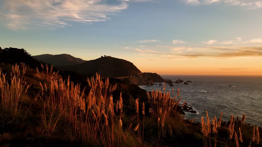 Aerial view of Bixby Creek Bridge along the dramatic coastline, where golden light bathes the cliffs and ocean, creating a stunning contrast, California, United States.