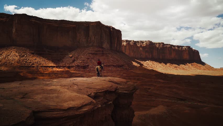 Native American Navajo rider on horseback overlooking Monument Valley with tail swaying. Cinemagraph