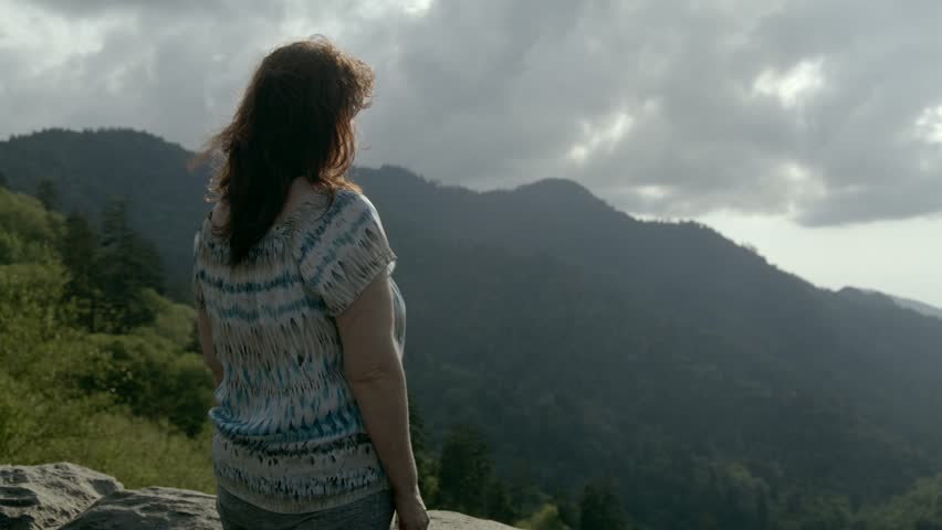 Middle aged woman looking at mountain view in the Great Smoky Mountains National Park in slow motion with pan right.