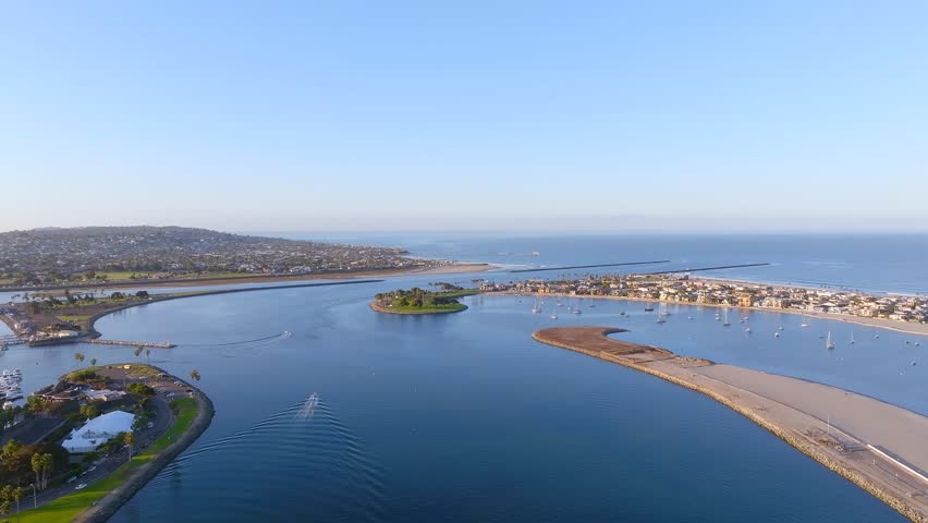 Aerial view of the bridge spanning across the water near the coast with the city in the background under a clear sky, San Diego, California, United States.