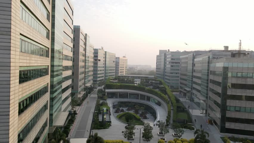 Sweeping drone shots of a sleek business park in Gurgaon, Haryana—glass skyscrapers, landscaped greenery, and urban infrastructure reflecting India’s growing global corporate presence.