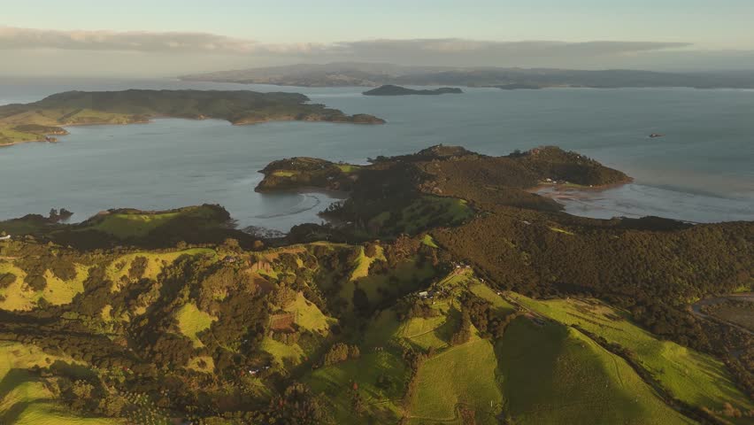 Peaceful and quaint coastline landscape of waiheke island, New Zealand. Cloudy sunset time with idyllic scenery and ocean water along coastline. Aerial wide shot.