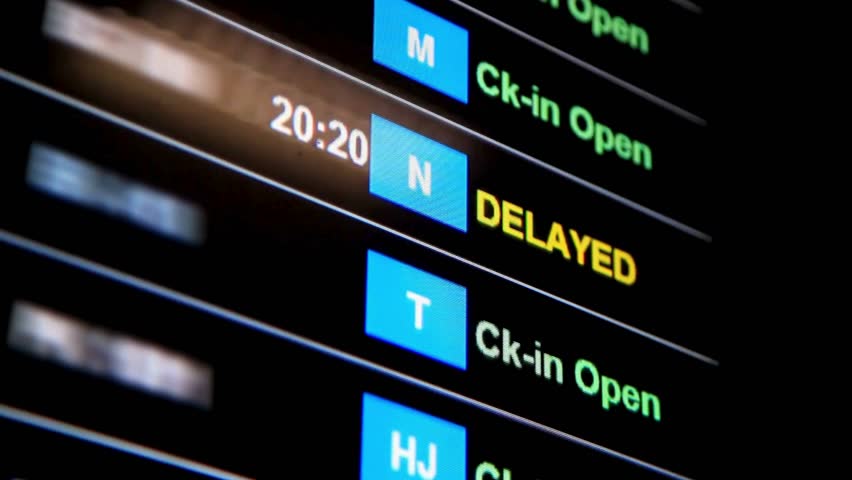 Flights delayed and canceled on departure board, flight delay footage. Device screen with airport flight information.