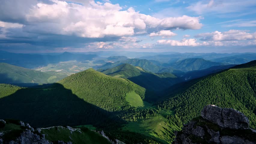 Carpathians mountain range timelapse with moving clouds, sunbeams lighting green valleys and peaks 