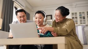 Grandparents and grandson spending quality time together at home while the elderly grandfather and grandmother support their young grandson with school homework and digital learning on a laptop - Powered by Shutterstock - Get 15% off with code: PIKWIZARD15