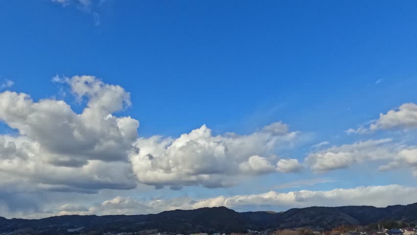 Winter blue sky, time-lapse with clouds flowing over the hills. 