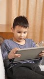 A boy plays games on a tablet while sitting on the couch. - Powered by Shutterstock - Get 15% off with code: PIKWIZARD15