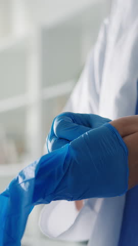Vertical Screen : Young Asia lady doctor or nurse worker surgeon preparing for the surgical operation and wearing hand gloves at health clinic or hospital office. Social distancing quarantine concept.