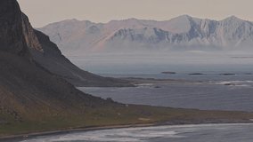 A slow sweeping aerial pan of Hvalnes cliffs, rugged terrain, scattered islets, and mist hovering near the coastline in Iceland. - Powered by Shutterstock - Get 15% off with code: PIKWIZARD15