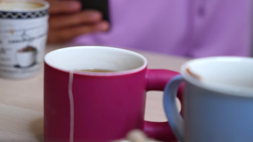 Warm lifestyle moment with tea mugs and a phone—ideal for relaxation, morning routine, casual tech use, remote work, or beverage-themed visuals.