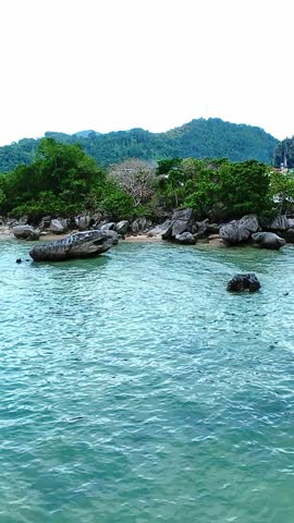 Rocky beach and green trees on calm coastal area of El Nido, Palawan from above