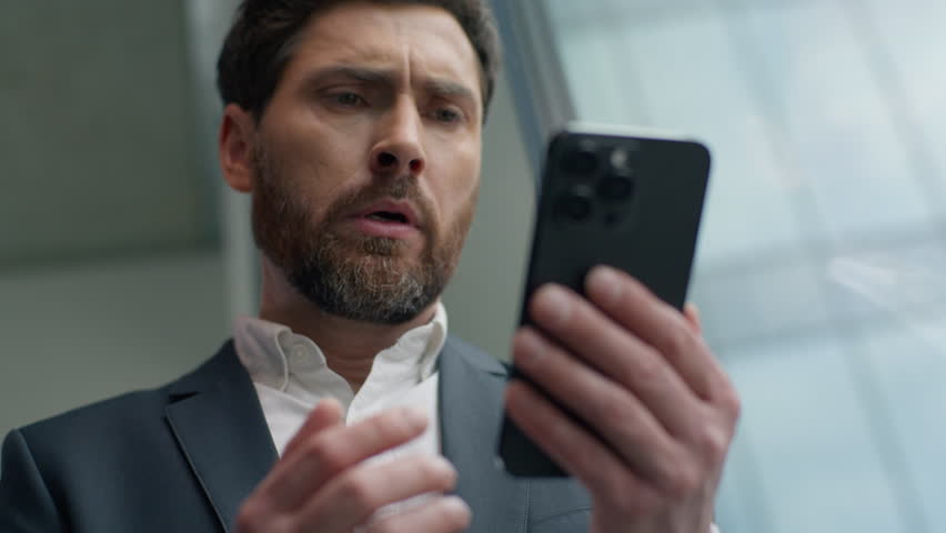 Close up unhappy frustrated Caucasian middle-aged business man reading bad news with mobile phone online failure upset in office worried stressed businessman male manager employer smartphone problem