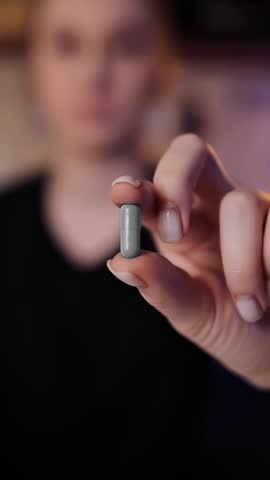 Person holds a capsule in their hand while focusing on its details in a close-up setting