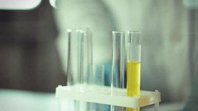 A scientist in gloves adds a powdered substance to a test tube containing yellow liquid. The laboratory environment is focused on chemical experimentation and research - Powered by Shutterstock - Get 15% off with code: PIKWIZARD15
