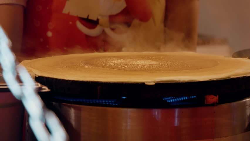 Experience the festive atmosphere of the Christmas market while watching a tasty pancake being prepared, blending sweet and salty flavors for the perfect treat.