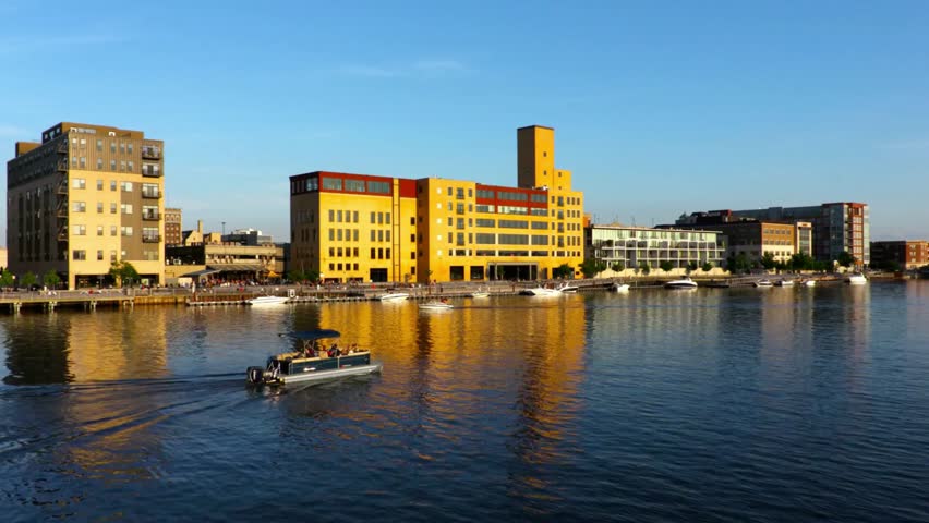 Milwaukee cityscape reflecting in the river with a boat cruising by on a sunny day