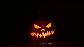 Pumpkin lantern glows with pulsing light in dark Halloween scene. Creepy carved face shines in night mood with seasonal mystery and fall decor - Powered by Shutterstock - Get 15% off with code: PIKWIZARD15
