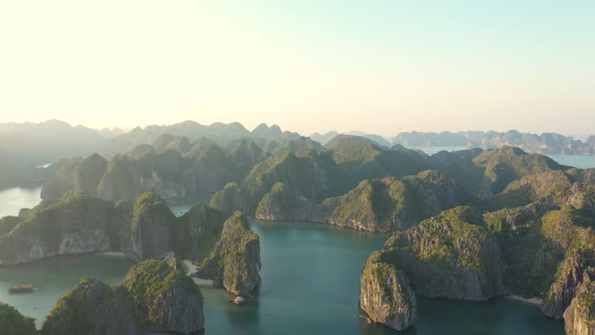 Golden hour illuminates the stunning landscape of Ha Long Bay, Vietnam, showcasing lush green islands amidst tranquil turquoise waters