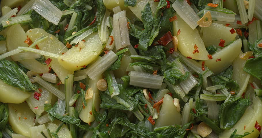 Background pattern of South Croatian Blitva s Krumpirom dish. The dish is made with boiled potatoes, swiss chard, garlic, and olive oil. Table spin.