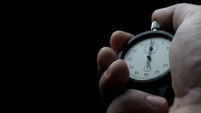 Male hand holds stopwatch and starts countdown. Second hand begins first tick. Concept of time control. Focus on precision and discipline. Dark background enhances intensity - Powered by Shutterstock - Get 15% off with code: PIKWIZARD15