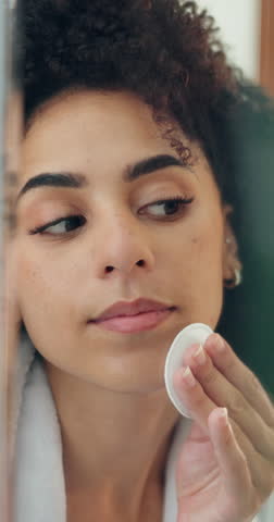 Woman, face and cotton pad with skincare for makeup removal or facial treatment in bathroom. Female person, patch or beauty with smile or mirror for skin toner, hygiene or gentle exfoliation in home