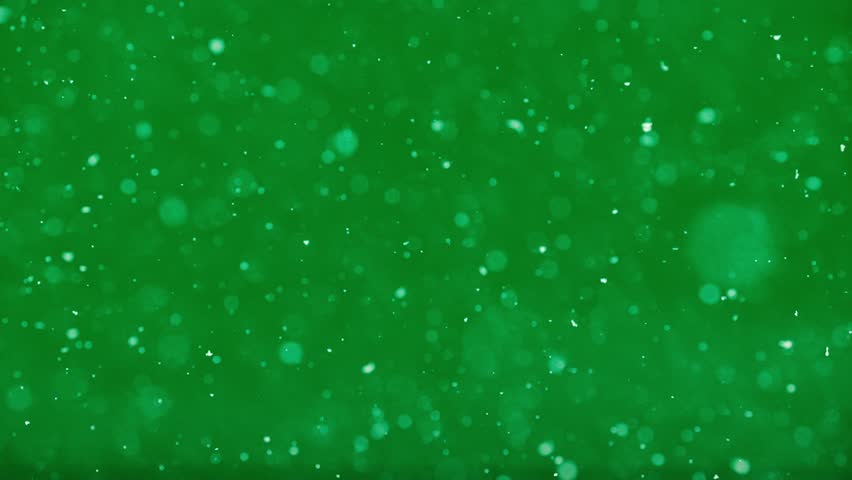 Dreamy slow snowflakes fall over neon green background with magical winter vibes