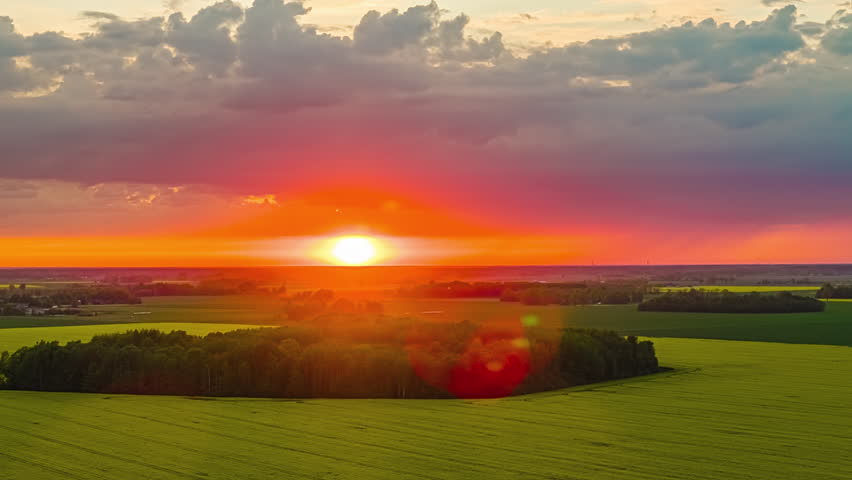 Red Sun Glowing During Sunset Over The Canola Fields. - aerial hyperlapse