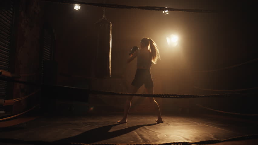 Sport activity and fitness, woman training alone in gym, do box with punch bag. Motivated sportswoman exercising alone in sportive hall at night, move to dream, future champion of female kickboxing